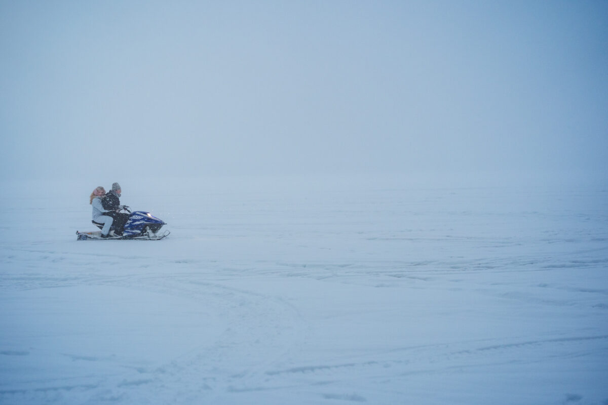 couple on a snowmobile during snow storm in Rovaniemi Finland